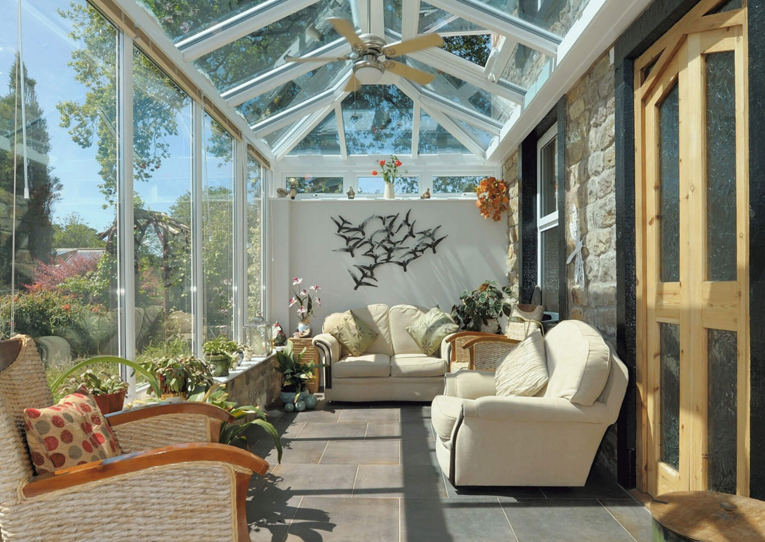A sofa, chair, and plants in a beautiful conservatory