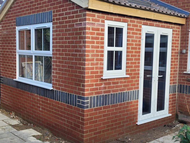 red brick extension with white casement windows and french doors