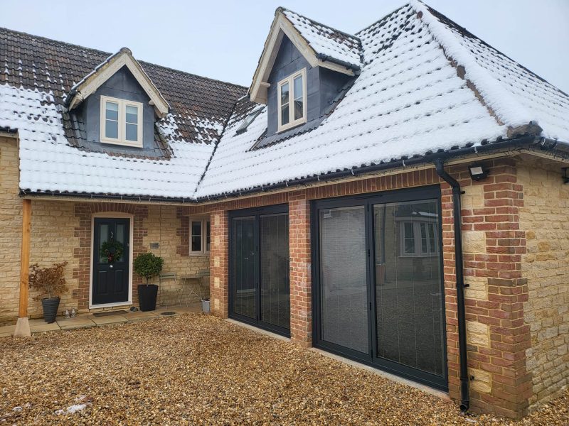 large house with black doors and snow on the roof
