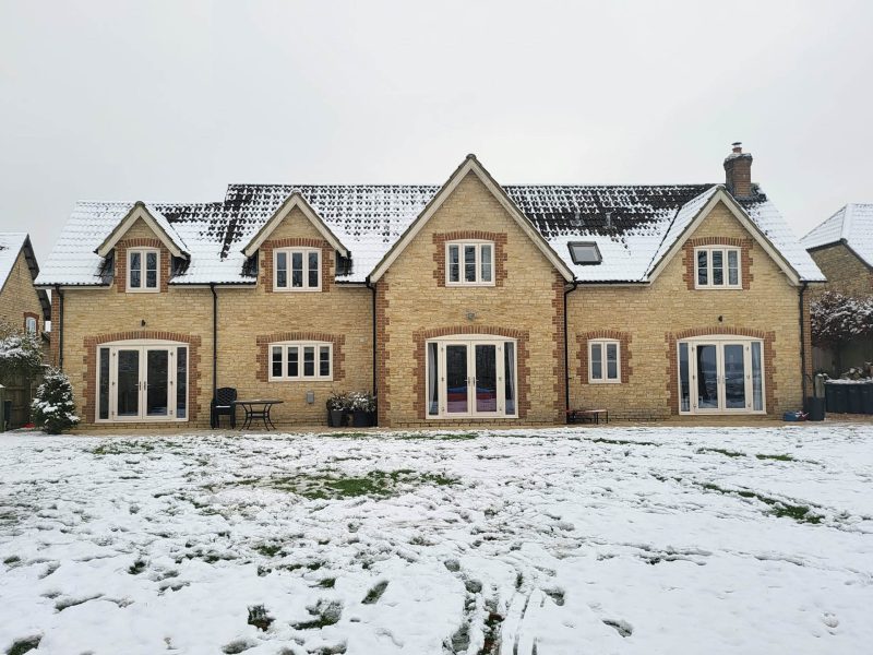 large house in winter with snow on roof and garden