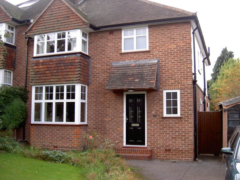 house with white bay windows and a black door